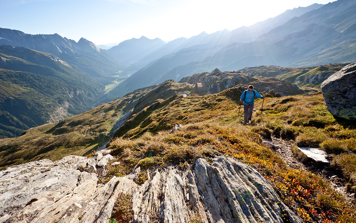 Auf dem Weg von Tegernsee nach Sterzing Wanderer auf alpiner Wiese. Sonnenstrahlen leuchten von hinten