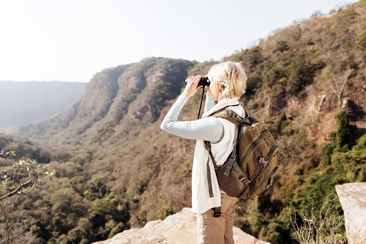 Frau mit Fernglas blickt in Ferne