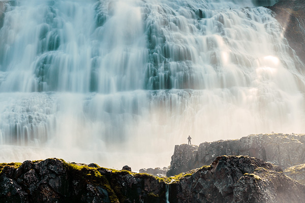 Person vor dem Dynjandi Wasserfall in Island