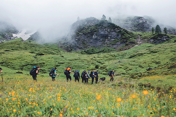 Wandergruppe auf einer Wiese auf der Alpenüberquerung Königssee - Drei Zinnen