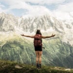 Wanderin mit ausgebreiteten Armen vor Bergkulisse in den Alpen
