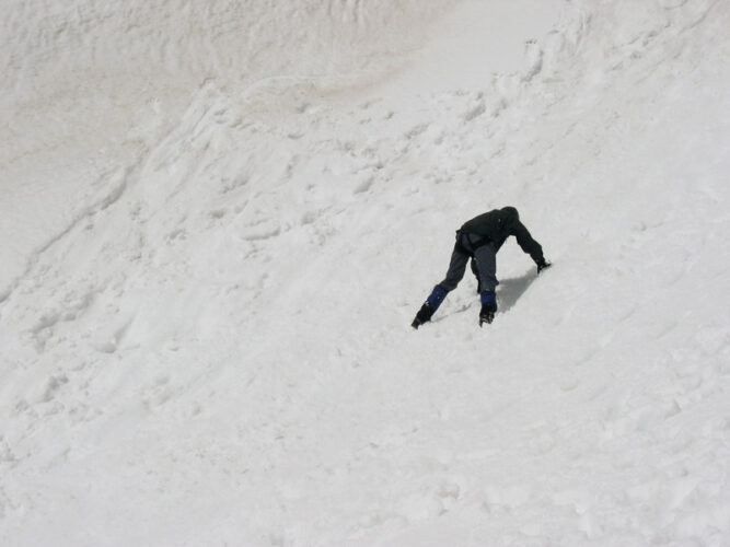 Mann in Liegestützhaltung auf einem Schneefeld.