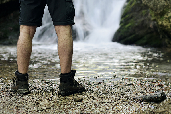 Wanderer in Wanderstiefeln vor einem Wasserfall