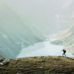 Wandernder vor einer Landschaft mit Bergen und Seen