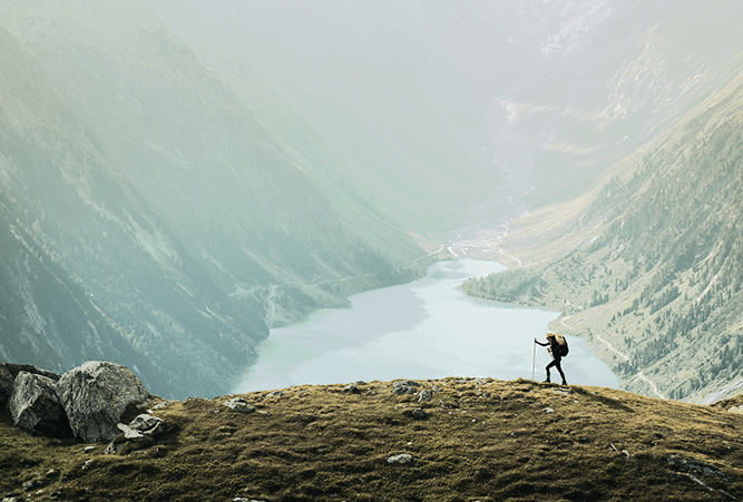 Wandernder vor einer Landschaft mit Bergen und Seen