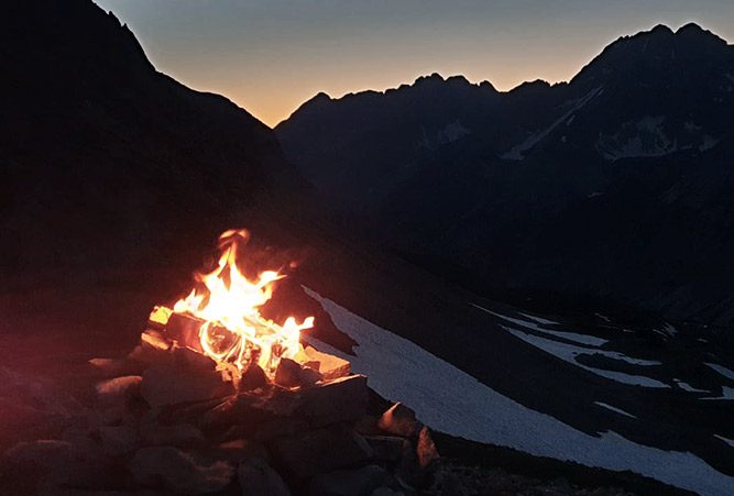 Bergsonnwend Feuer vor dunklen Bergen, Abend