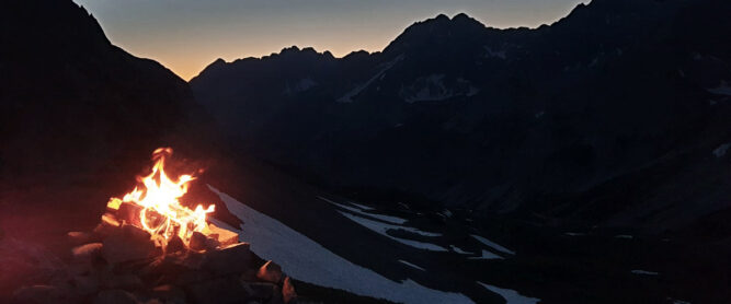 Bergsonnwend Feuer vor dunklen Bergen, Abend