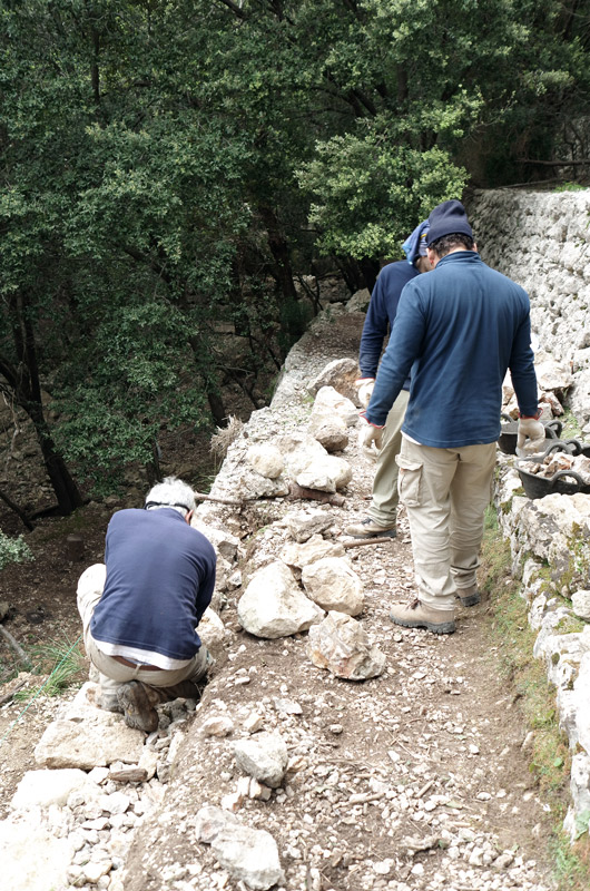 Zwei Wanderer an einer steilen Stelle neben einer Trockensteinmauer