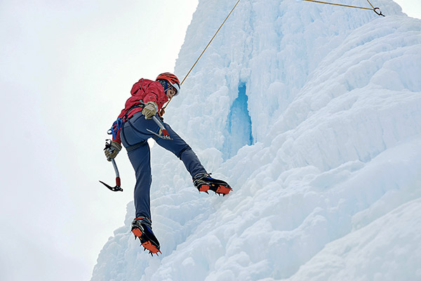 Eiskletterin beim Abseilen am Wasserfall