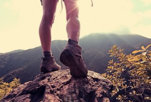 Beide einer Frau, die auf dem Felsen eines Berggipfels steht.