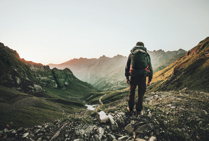 Mann wandert bei Sonnenuntergang im Sommer allein durch die Bergwildnis