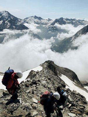 Bergsteiger mit Helm am Gipfel, Schweiz