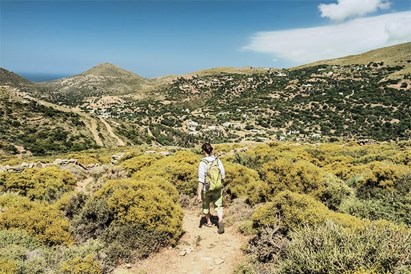 Wanderin auf schmalem Pfad in grüner Landschaft auf der griechischen Insel Andros