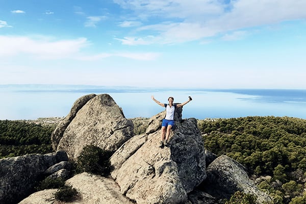 Wanderin ohne Höhenangst mit hochgereckten Armen auf einem Felsen auf Chalkidiki