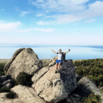 Wanderin mit hochgereckten Armen auf einem Felsen auf Chalkidiki