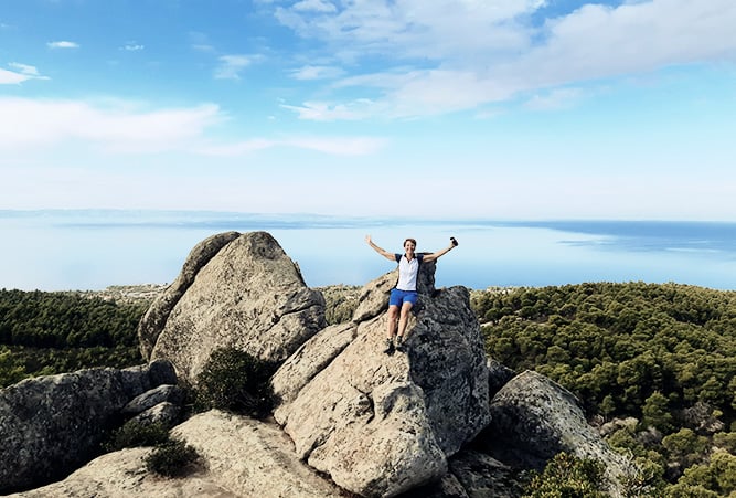 Wanderin mit hochgereckten Armen auf einem Felsen auf Chalkidiki
