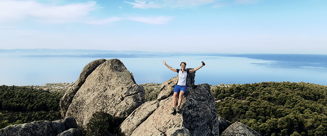 Wanderin mit hochgereckten Armen auf einem Felsen auf Chaldidiki