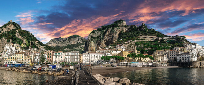 Panorama auf Küstenstadt Amalfi. Sonnenuntergang mit gelb und rot leuchtenden Wolken