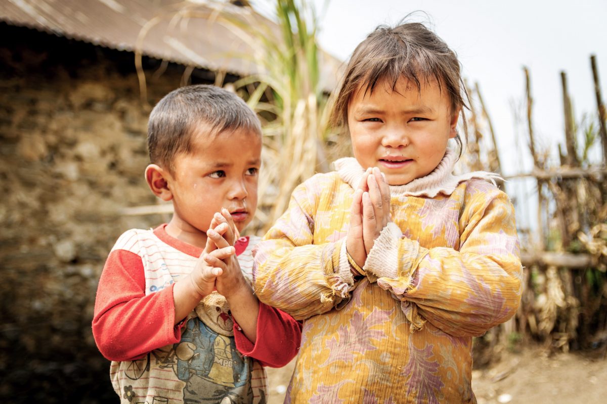Zwei Kinder machen die Geste Namaste.