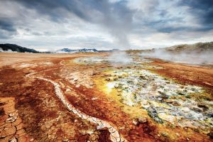 Gelbe und goldrote Gesteinsfläche mit dampfenden Quellen