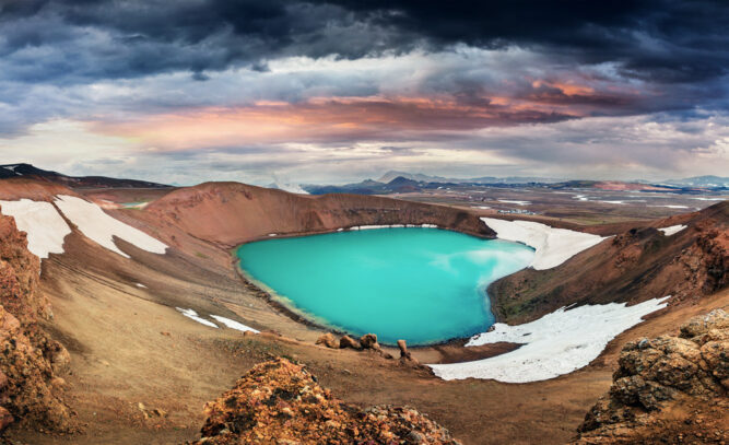 Kleiner helltürkiser See in einem Krater, Schneefelder. Viti Krater, Island.