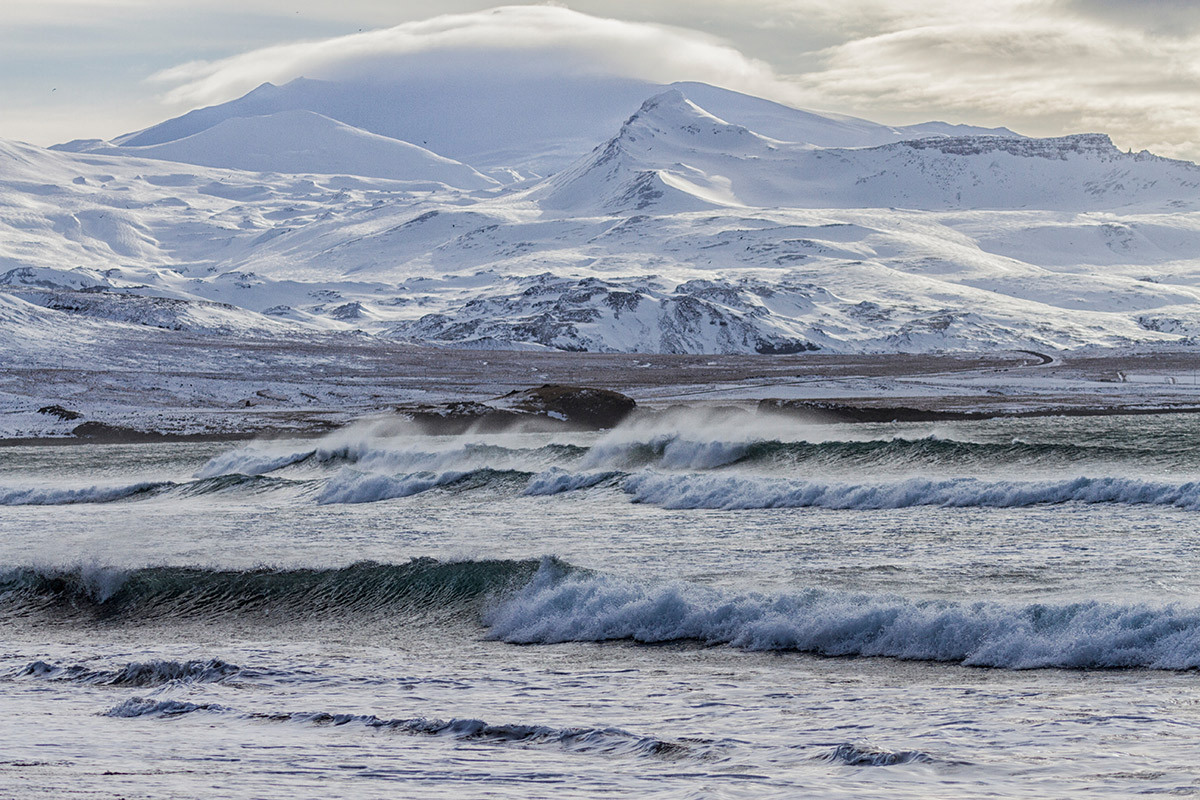 meer mit wellen, verschneite berge im Hintergrund