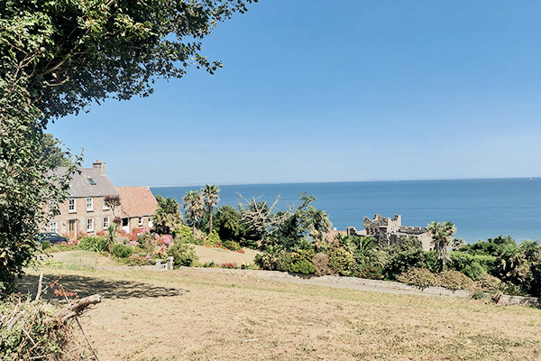 Blick auf die Küste mit einer Burg an der Fliquet Bay auf Jersey