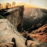 Mann sitzt auf dem Boden und blickt in den Sonnenuntergang im Yosemite Nationalpark, USA. © Jordan Pulmano