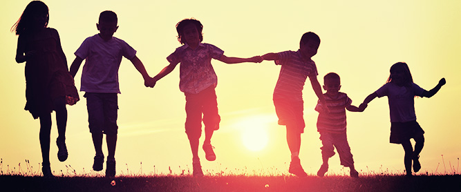 6 Hände haltende Kinder im Sonnenuntergang