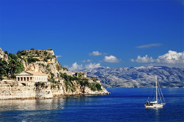 Eine Segelboot vor der Küste von KOrfu und einem griechischen Tempel