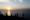 untergehende Sonne am Horizont, davor meer und silhouetten von menschen