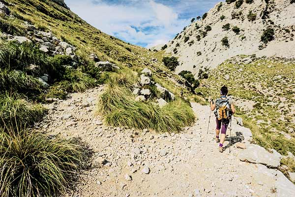 Wanderin auf Steinpfad zwischen begrünten Hängen auf Mallorca