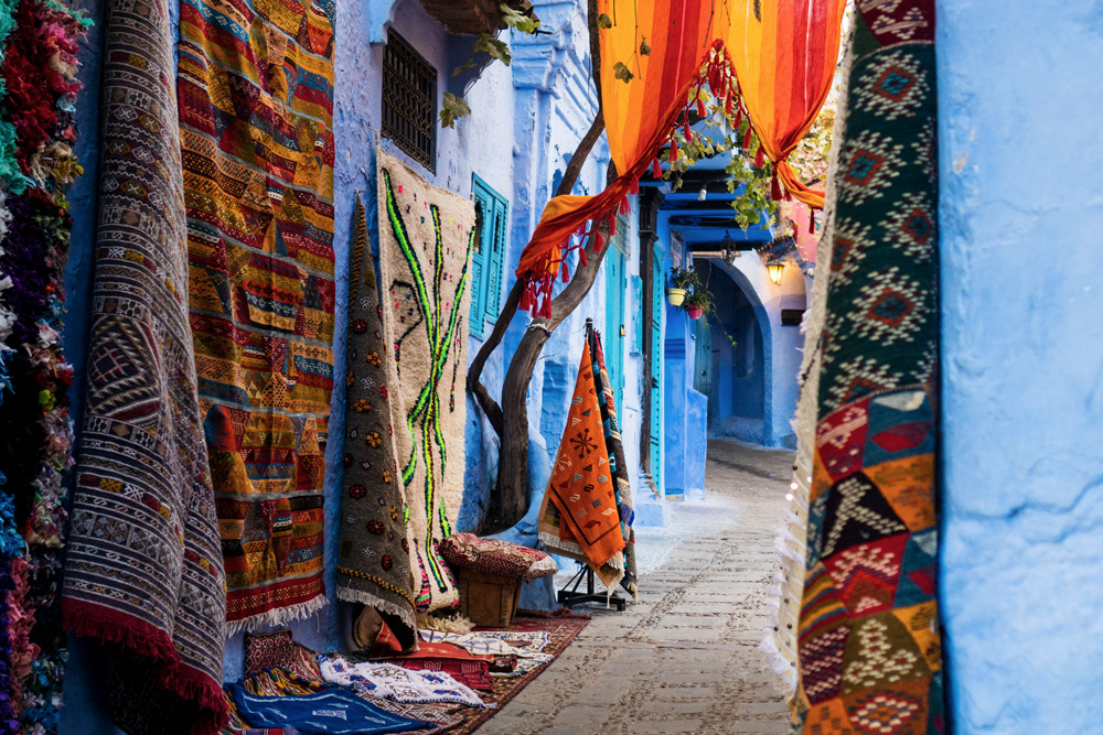 bunte Teppiche an blauer Wand in enger Gasse