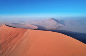 Blick auf rötliche große Sanddünen, blauer Himmel