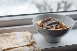 Keramikschüssel mit getrockneten Fischstückchen auf Fensterbrett