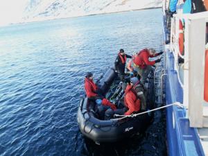 Mehrere Personen steigen in ein schwarzes Schlauchboot ein