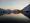Himmel kurz nach Sonnenuntergang an Meeresbucht, schwarzes Wasser und verschneite Berge