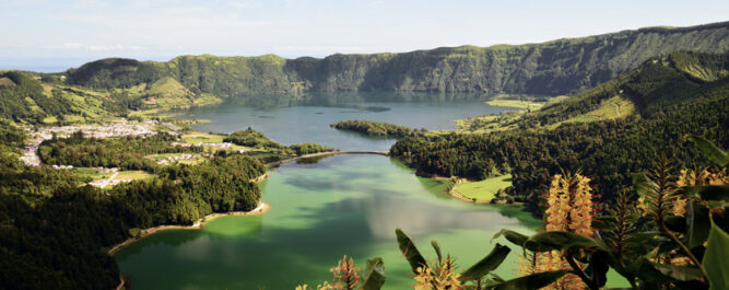Panoramablick auf den grünen Kratersee umgeben von vulkanischen Bergen und sommerlicher Landschaft