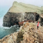 Wanderin mit roter Mütze und rotem Pulli an der Küste von Ponta de São Lourenço im Osten von Madeira, Portugal