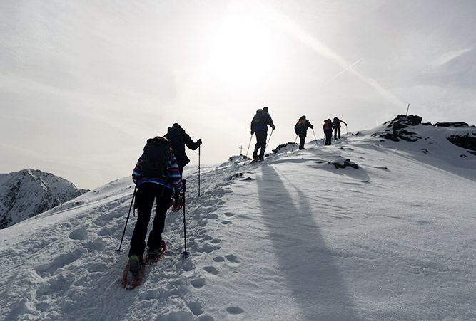 Gruppe Schneeschuhwanderer besteigt verschneiten Gipfel