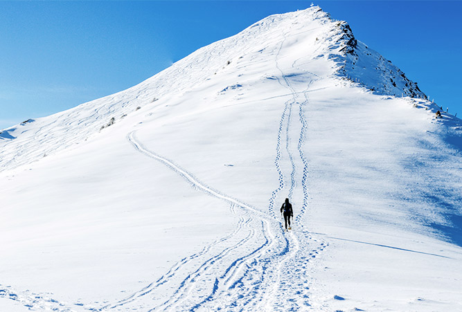 Einsamer Schneeschuhgeher besteigt verschneiten Berggipfel