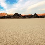 Der trockene, Rissige Boden des Death Valley Nationalpark mit Ausblick auf die Berge. © Shutterstock