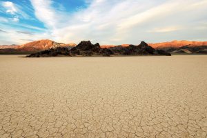 Der trockene, rissige Boden des Death Valley Nationalpark mit Ausblick auf die Berge. © Shutterstock