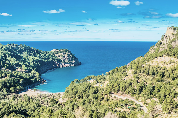 Blick auf das Meer, den Strand und die Hügel in der Cala Tuent auf Mallorca