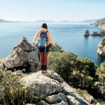 Wanderin mit Trekkingstöcken an einer Klippe bei Formentor auf Mallorca