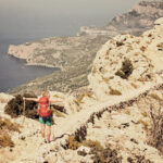 Wanderin mit ausgestreckten Armen an der Küste auf dem GR221 auf Mallorca