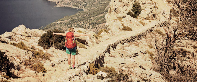 Wanderin mit ausgestreckten Armen an der Küste auf dem GR221 auf Mallorca