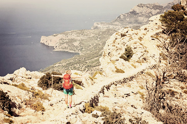 Wanderin mit ausgestreckten Armen an der Küste auf dem GR221 auf Mallorca