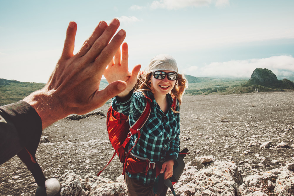 zwei Menschen, die sich ein high5 geben; frau mit sonnenbrille und bandana auf dem kopf