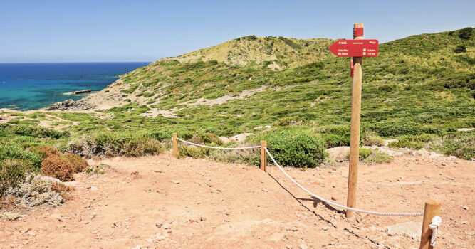 Wegweiser am Wanderweg an der Küste nahe der Cala Pilar auf Menorca, Spanien